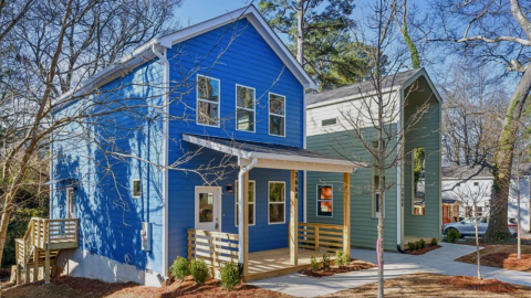 A row of colorful houses with affordable prices under blue skies in Atlanta in front of a quiet street. 