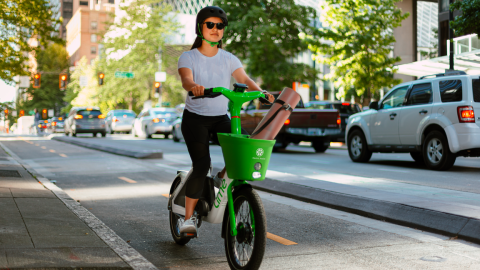 A photo of a person with a black helmet riding a green and white ebike in a city.