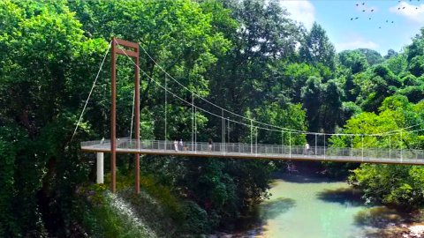 A bridge image over a blue creek near many trees in Atlanta under blue skies. 