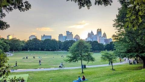 A photo of a city park in the evening with green grass and hazy nice skies. 