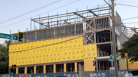 A photo of a large long steel and yellow-insulation-clad building under blue skies near a wide street and bike path in Atlanta.