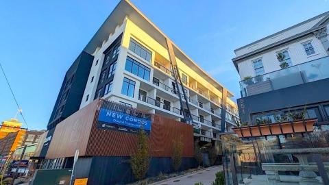 A photo of a large white and black condo building under blue skies near a wide street in Atlanta.
