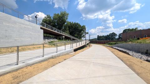 A photo of a large concrete pathway and infrastructure in Atlanta under blue skies with many buildings and homes and trees nearby.