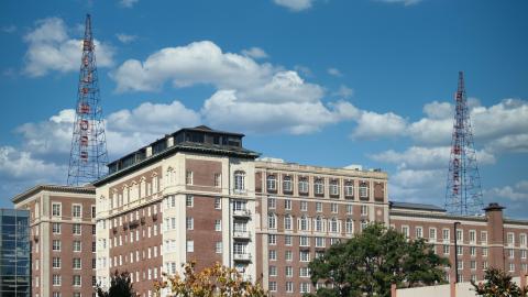 A photo of an old ornate brick and stone building under blue skies in Atlanta near many tall buildings.