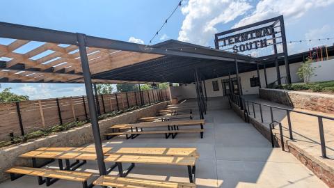 A large food hall and retail hub made from two old warehouses in Atlanta under blue skies near wide streets and a parking lot.