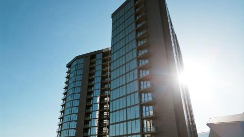 A photo of a glassy high-rise under blue skies with white modern interiors in Atlanta near a huge gray football stadium.