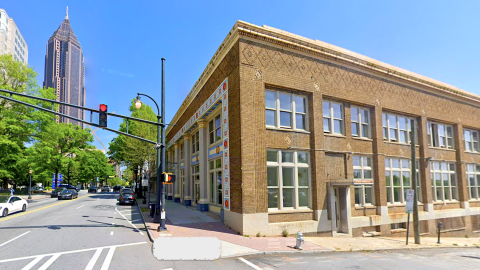 A photo of a large brick building amid skyscrapers under blue skies in Atlanta. 