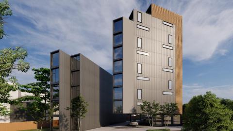A modern gray and brown stack of apartments and office spaces under blue skies near a wide street on Atlanta's southside.