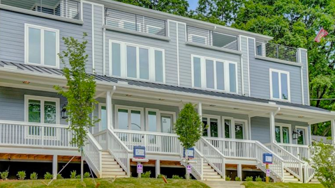 A photo of a large townhome row with blue-gray exteriors and modern interiors with custom woodworking, under blue skies in Atlanta.