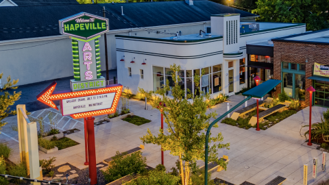 A photo of a large new sign on a street corner with red and green lights and "Welcome to Hapeville" at the top. 