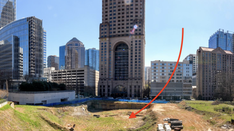 A large wide open greenspace among many tall buildings under blues skies near wide streets in Atlanta.