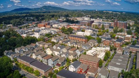 An aerial photo of an Atlanta suburban city with a large downtown and a mountain in the distance, under blue skies.