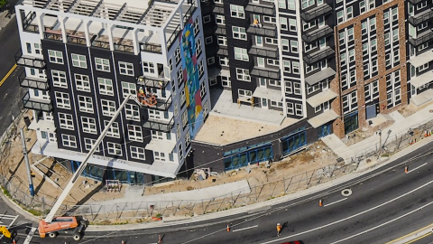 An image of a large new apartment complex near a wide Atlanta street with a huge mural and many balconies.