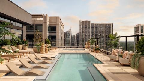 A photo of a large new upscale student housing building with a pool on the roof and cozy modern beige interiors for student housing on a busy main street in Atlanta.
