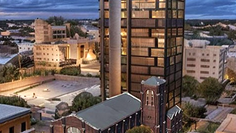 A rendering showing a large new tower in downtown Atlanta behind a historic church near many other buildings under blue purple skies.