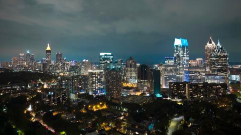 An aerial photo of a large city with a long spiky skyline under thick clouds near a large park.