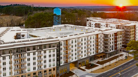 A modern-style new apartment complex with two large buildings and many lounge areas off a wide street in Atlanta, with new stylish modern apartments, with city and tree views beyond.