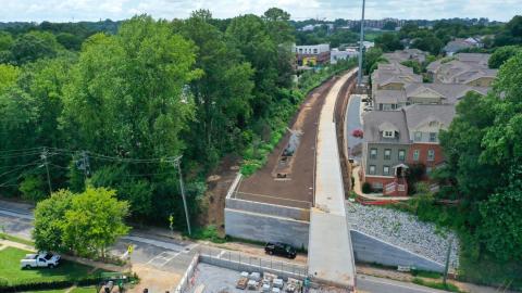 A drone photo of a large section of newly paved trail along many houses and wide streets in Atlanta between a lot of trees.