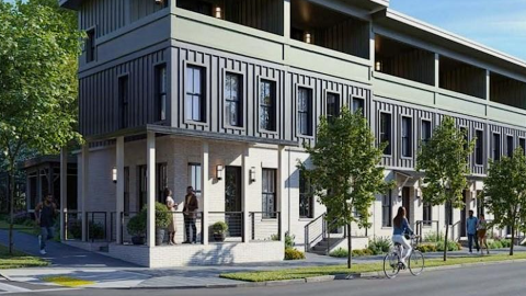 An image of a long row of townhomes under blue skies with three stories and terraces up top overlooking a wide street. 