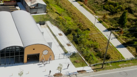 An overview of a large bike shop building next to a trail in southwest Atlanta with many trees around.
