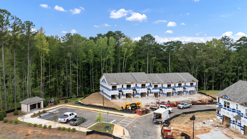 An image of a large new townhome community being built in Georgia woods outside Atlanta under blue skies. 