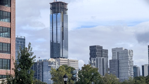 A photo of a glassy high-rise building under blue gray skies in Atlanta with many other towers around.