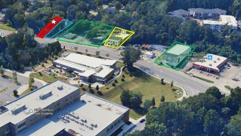 An overview of a neighborhood's commercial district in Atlanta near many trees and buildings and a wide street.