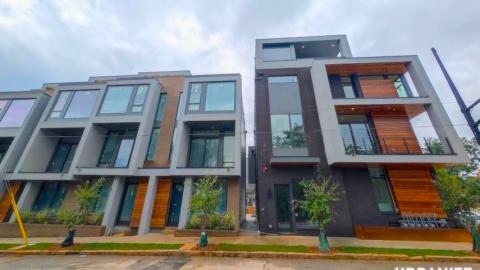A photo of a large modern townhome project under gray skies in Atlanta near a wide street. 