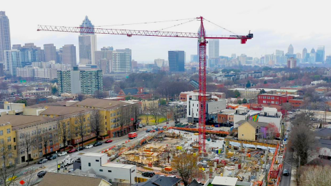 An aerial photo of a large construction site in Atlanta under gray skies with a large red crane in the middle. 