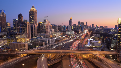 An aerial photo of a city in twilight with a huge highway in the middle. 