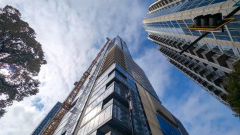A photo of a huge new skyrise set among many other buildings under bright blue skies near many tall buildings in Atlanta. 