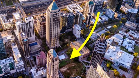An overview of a huge park site in Atlanta near a wide highway and many tall buildings with skyscrapers around. 
