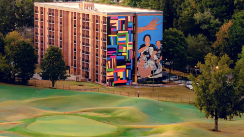 A photo of a large new affordable housing apartment project near Atlanta with many trees and wide parking areas around.