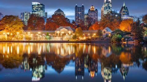 A photo at night over Piedmont Park in Atlanta overlooking a large city and many highways with glowing clouds above.