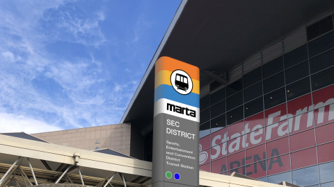 An image of an older train station in downtown Atlanta with new signage near a huge stadium. 
