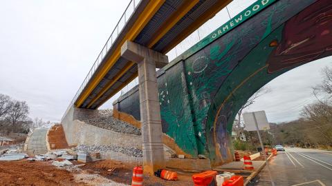 Construction on a large new multi-use trail near many homes and trees is shown with dirt of construction in Atlanta under gray winter skies.