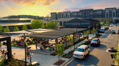 An aerial view of a new mixed-use development project north of Atlanta with many buildings under a blue and orange sunset. 