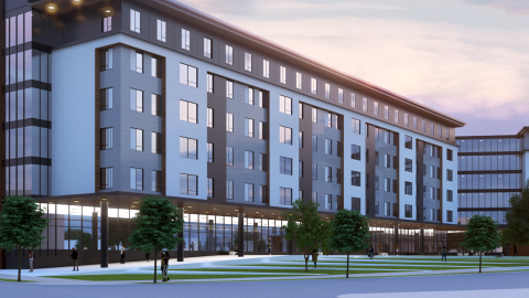 An image of a site where large student housing building is bound for a large plot of empty land beside a wide street under blue orange skies.