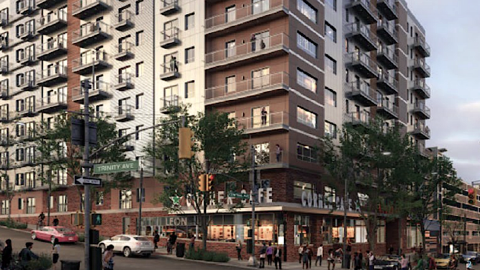 A corner mixed-use building under gray-blue skies in Atlanta near two wide streets and trees.