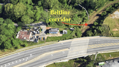 An overview of a trail site and junkyard property next to wide street and many trees where a new townhome project is proposed in Atlanta with 12 units.
