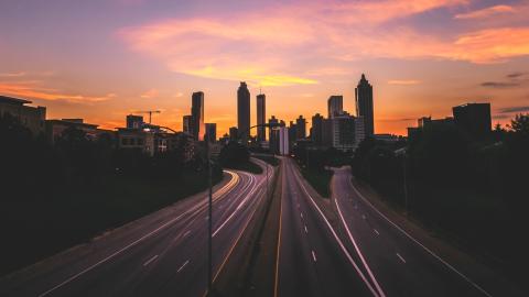 A photo of a large city skyline at dusk over a wide highway and city street in Atlanta. 