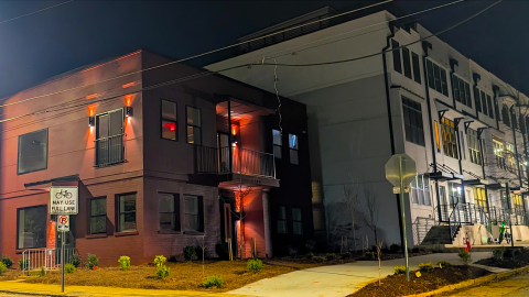 An image of a newly expanded corner building in the East Atlanta Neighborhoods near a long row of townhomes under night skies. 