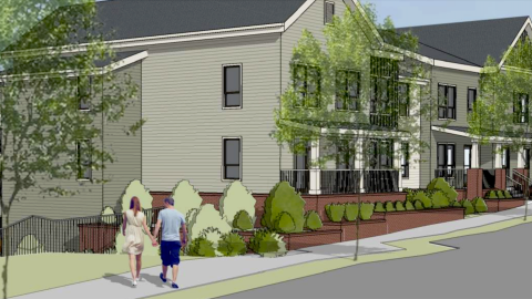 An image of a green gray and black new development on a corner with trees and two people walking next to it.