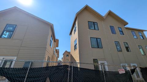 A photo of a large townhome project with tan siding walls under construction in Atlanta under blue skies.