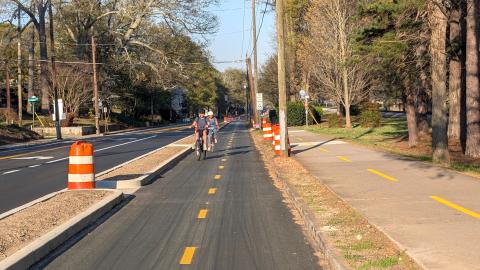 A photo of a protected new cycle track for bikes and other mobility devices near trees and a wide street east of Atlanta in Decatur.