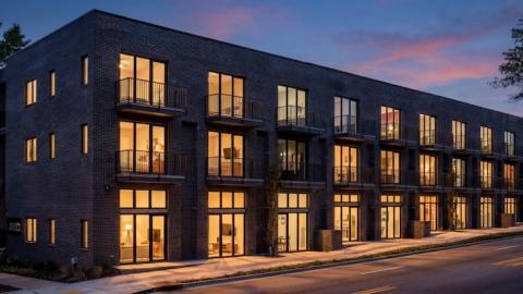An image of a brick apartment complex with many lofts near two wide streets and many trees, with white modern interiors in Atlanta.