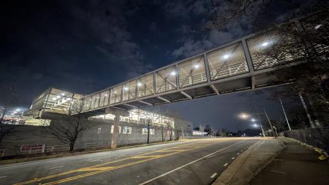 A nighttime photo of a large pedestrian bridge at an Atlanta transit station.