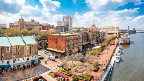 An aerial shot of a city on a wide river under blue skies in Georgia. 