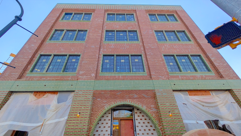 An image of a multi-building project with a mason's lodge and brick corner building on Atlanta's eastside overlooking two wide streets, under blue skies. 