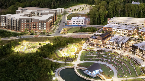 An image of a large apartment development in the corner of a bigger city center near a pond feature outside Atlanta. 